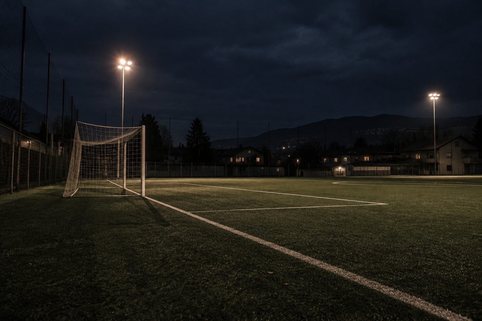 Un campo di quartiere di sera, con la porta illuminata dai fari